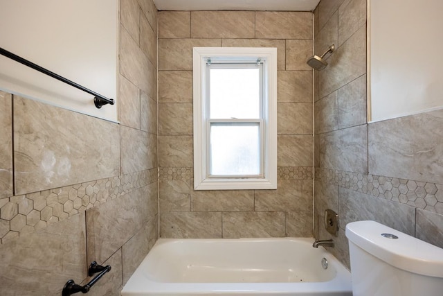 bathroom featuring tiled shower / bath combo, toilet, and tile walls