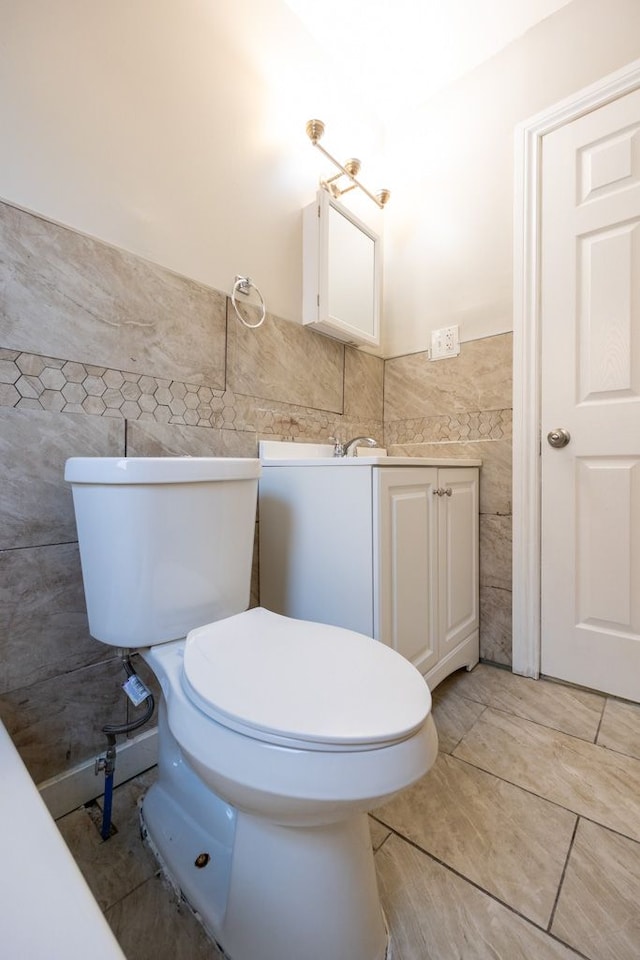 bathroom with vanity, toilet, and tile walls