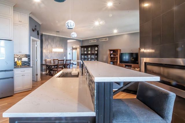 kitchen with crown molding, a spacious island, backsplash, a sink, and visible vents