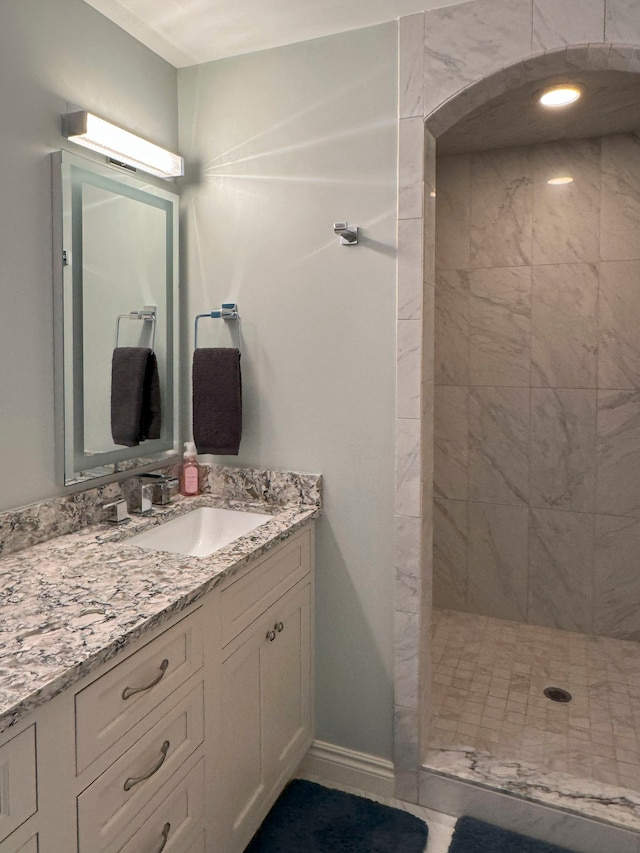 bathroom featuring tiled shower and vanity
