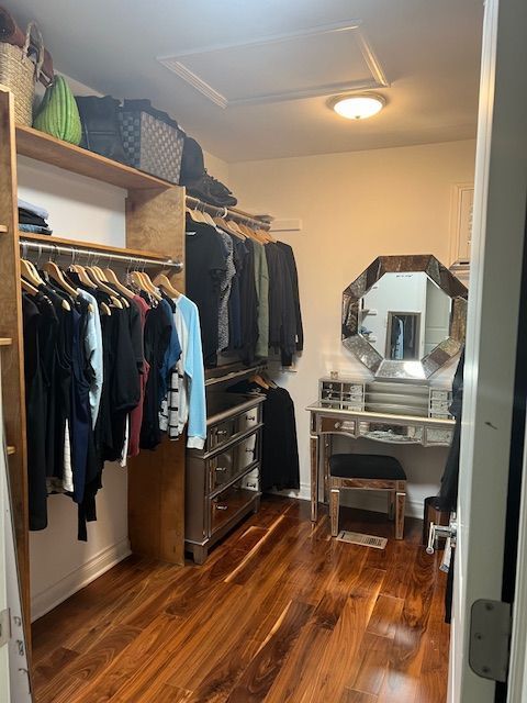 walk in closet featuring attic access and dark wood-style floors