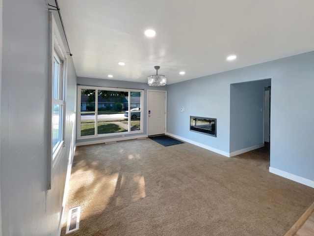 unfurnished living room featuring carpet floors and an inviting chandelier