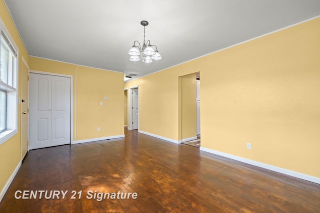 unfurnished room featuring a notable chandelier, dark hardwood / wood-style floors, and a healthy amount of sunlight