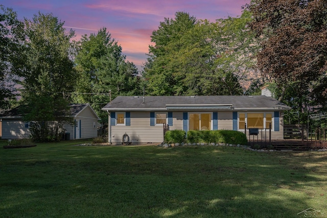 back house at dusk with a lawn