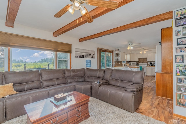 living room featuring beamed ceiling, light hardwood / wood-style flooring, and a healthy amount of sunlight