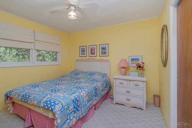 bedroom with ceiling fan, light colored carpet, and wooden walls