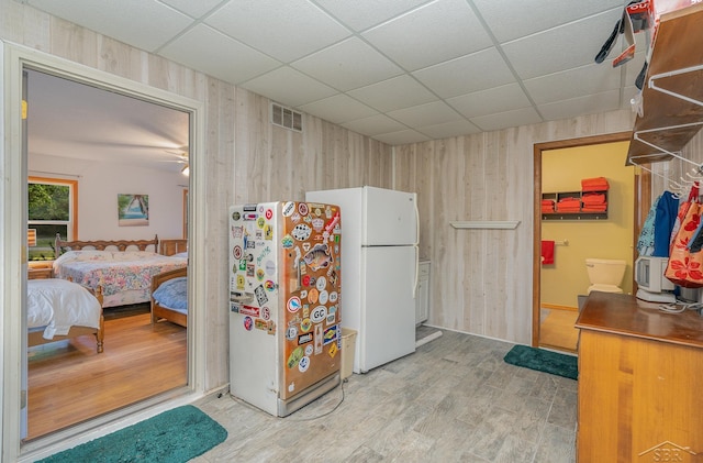 kitchen featuring wood walls, hardwood / wood-style floors, and a drop ceiling