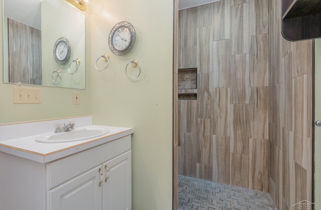 bathroom featuring a tile shower and vanity