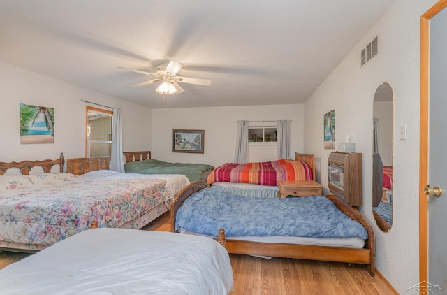 bedroom with heating unit, ceiling fan, and hardwood / wood-style floors