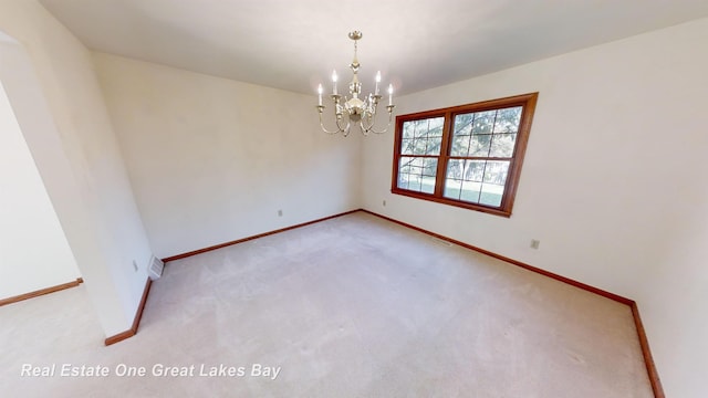 empty room featuring light carpet and a chandelier