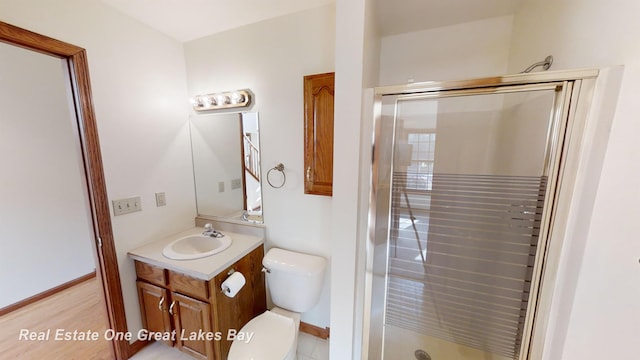 bathroom with hardwood / wood-style floors, vanity, toilet, and walk in shower