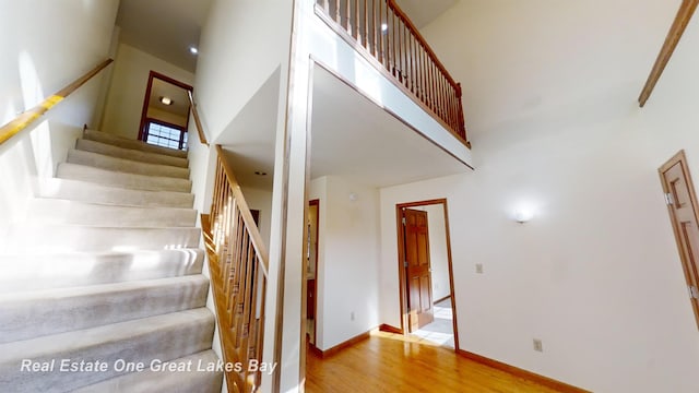 staircase featuring hardwood / wood-style flooring and a high ceiling