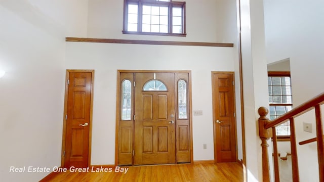 foyer entrance featuring a towering ceiling and light hardwood / wood-style floors