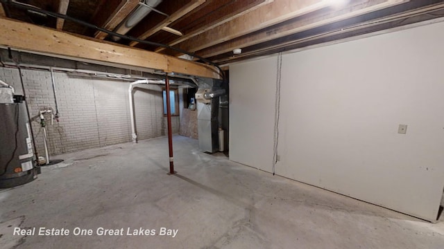 basement featuring brick wall and gas water heater