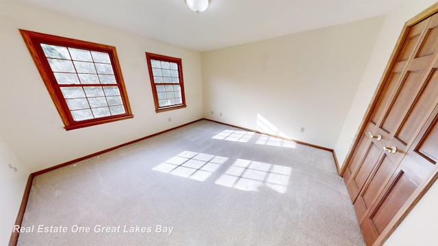 unfurnished bedroom with light colored carpet and a closet