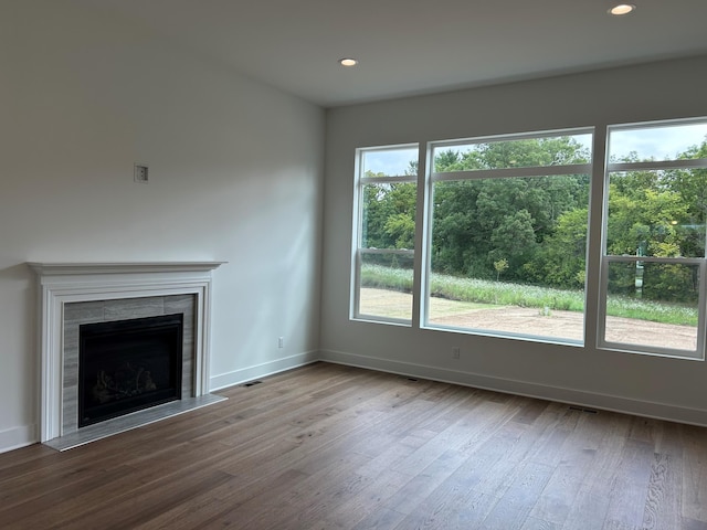 unfurnished living room with a tiled fireplace and wood-type flooring