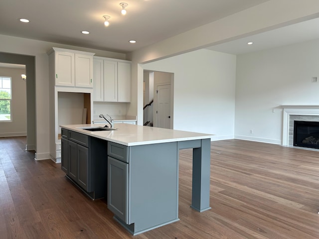 kitchen featuring gray cabinetry, sink, hardwood / wood-style flooring, an island with sink, and white cabinetry