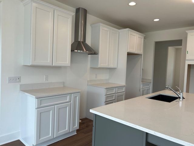 kitchen with light stone countertops, wall chimney exhaust hood, sink, dark hardwood / wood-style floors, and white cabinetry