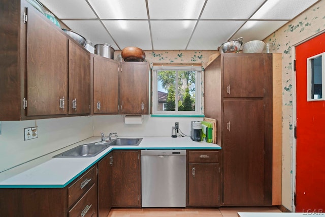 kitchen featuring sink, stainless steel dishwasher, a paneled ceiling, dark brown cabinets, and light tile patterned floors