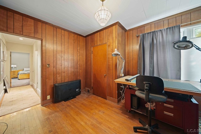 home office with wood walls, light wood-type flooring, and ornamental molding