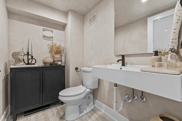 bathroom featuring wood-type flooring and toilet