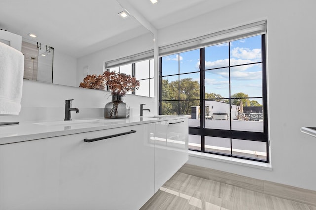 kitchen featuring a healthy amount of sunlight, white cabinetry, sink, and light hardwood / wood-style flooring