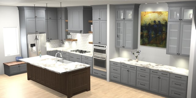 kitchen featuring sink, light hardwood / wood-style flooring, an island with sink, decorative backsplash, and appliances with stainless steel finishes