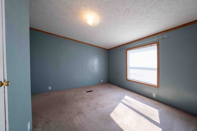 unfurnished room with carpet flooring, a textured ceiling, and ornamental molding