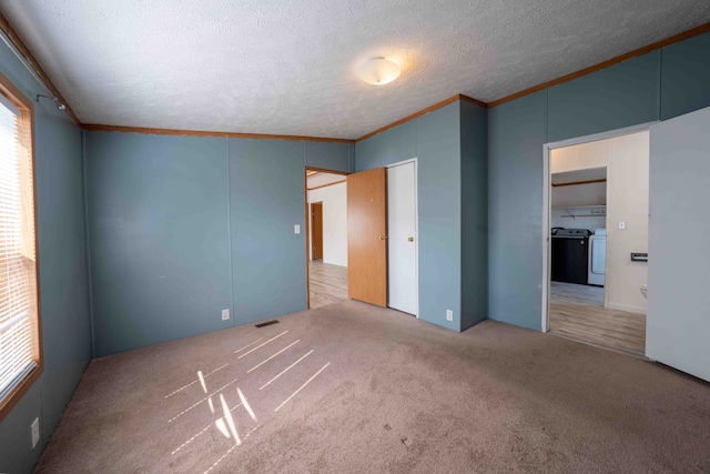 unfurnished bedroom featuring independent washer and dryer, a textured ceiling, light colored carpet, and crown molding