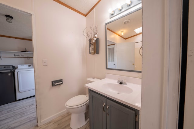 bathroom with crown molding, washer and clothes dryer, and wood-type flooring