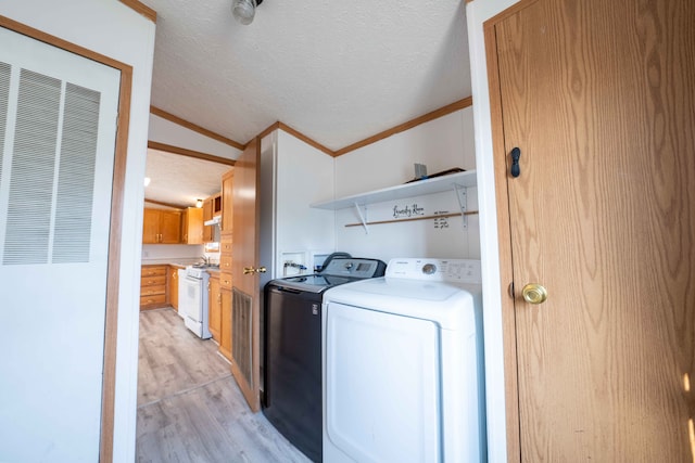 washroom with crown molding, light wood-type flooring, a textured ceiling, and separate washer and dryer