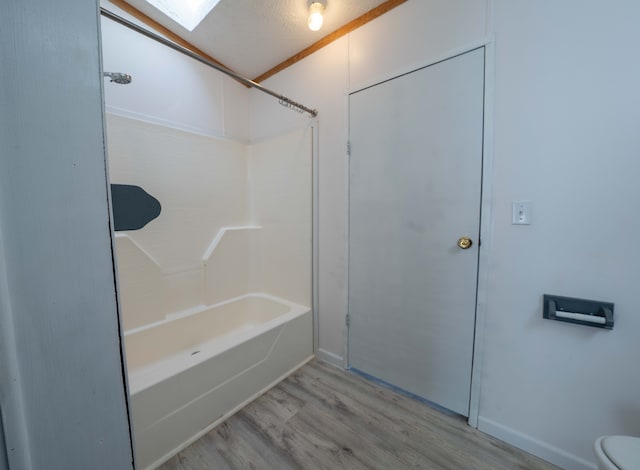 bathroom featuring shower / bath combination, hardwood / wood-style flooring, toilet, and a skylight