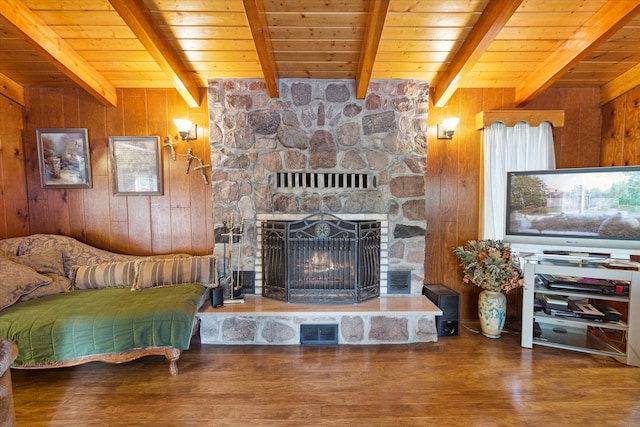 living room featuring beamed ceiling, hardwood / wood-style floors, a fireplace, and wood walls