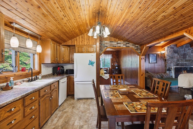 kitchen featuring white appliances, vaulted ceiling, sink, pendant lighting, and a chandelier