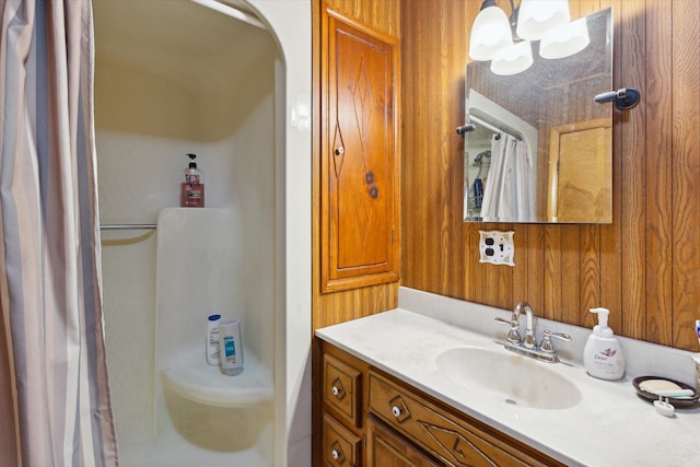 bathroom with vanity, walk in shower, wooden walls, and an inviting chandelier