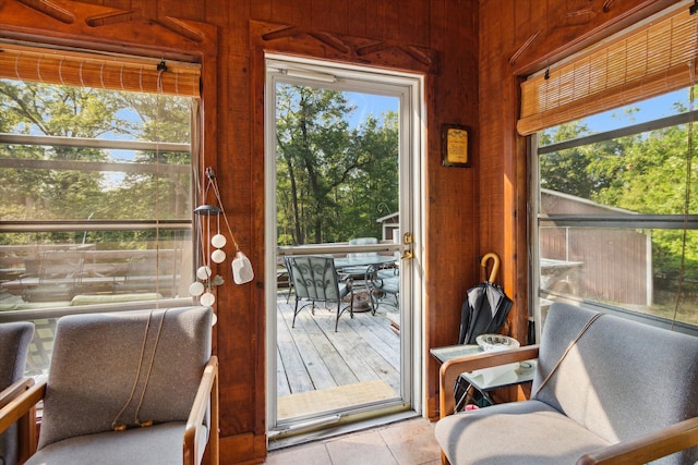 doorway to outside with wooden walls and light tile patterned floors