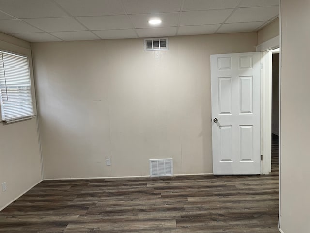 unfurnished room featuring a paneled ceiling and dark hardwood / wood-style floors