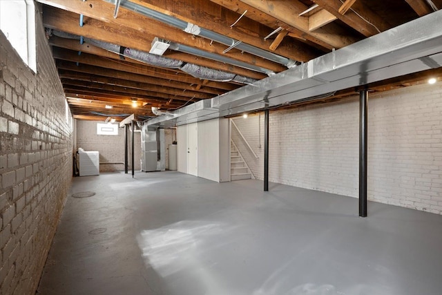 basement featuring heating unit, water heater, and brick wall