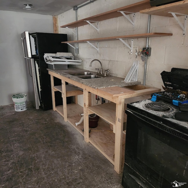 kitchen with black electric range, sink, and stainless steel fridge