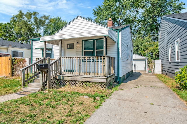 bungalow featuring a porch, an outdoor structure, and a garage