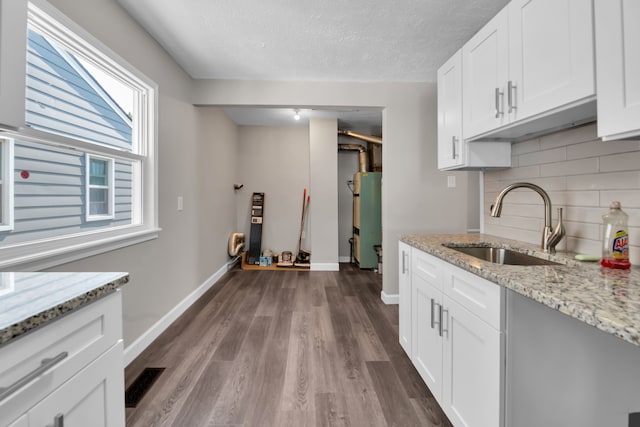 kitchen featuring light stone countertops, light hardwood / wood-style flooring, white cabinetry, and sink