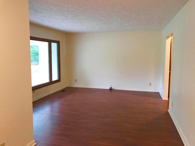 unfurnished room with a textured ceiling and dark wood-type flooring