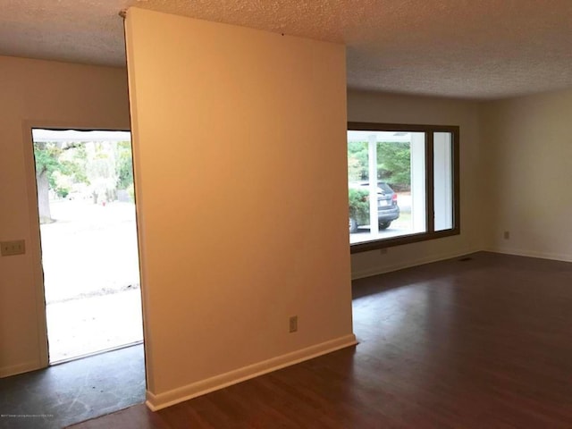 empty room with dark hardwood / wood-style flooring and a textured ceiling