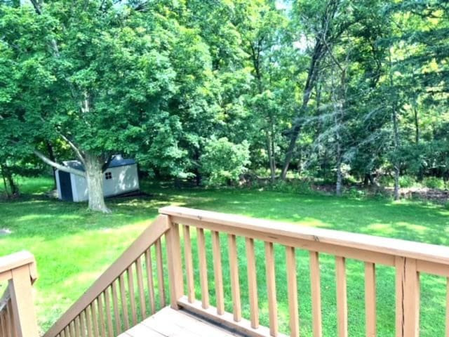 wooden deck featuring a lawn and a storage unit