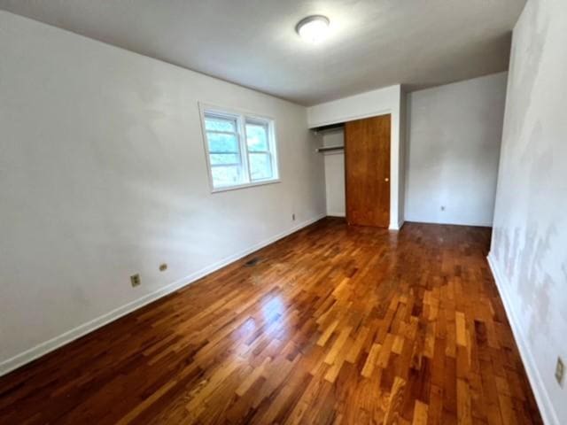 unfurnished bedroom featuring dark hardwood / wood-style flooring and a closet