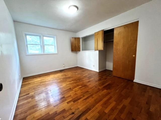 unfurnished bedroom featuring a closet and dark hardwood / wood-style flooring