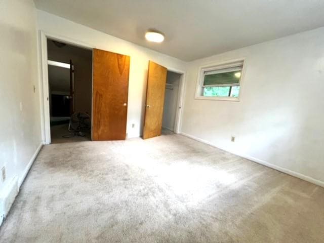 unfurnished bedroom featuring multiple closets and light colored carpet