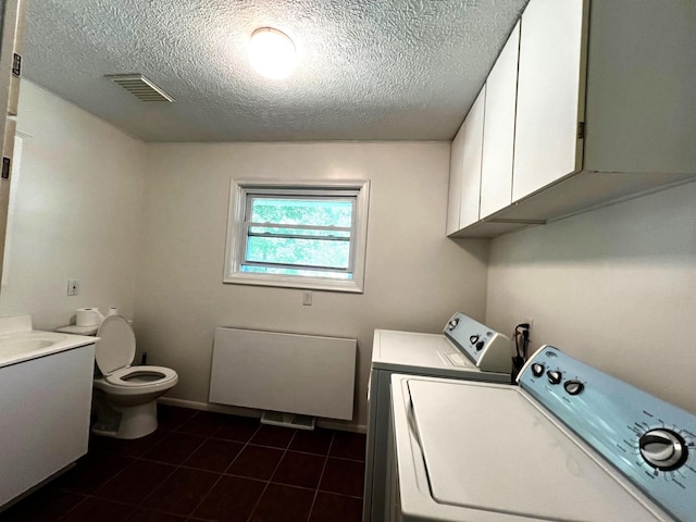 clothes washing area featuring a textured ceiling, dark tile patterned flooring, and washing machine and clothes dryer