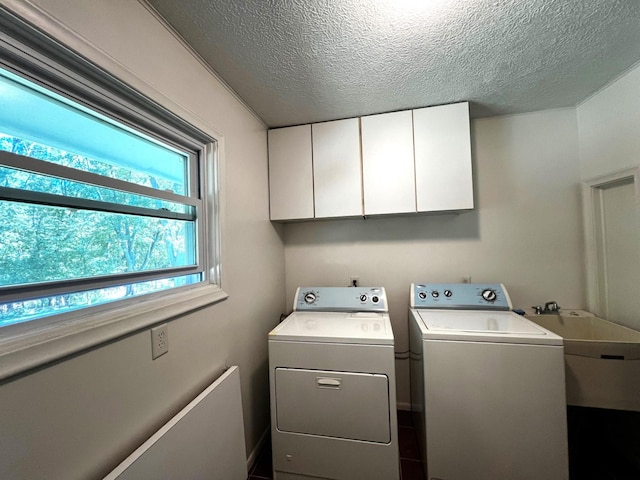 laundry area featuring cabinets, a textured ceiling, sink, and washing machine and clothes dryer