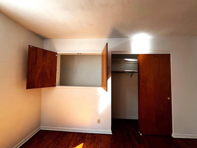 unfurnished bedroom featuring dark hardwood / wood-style flooring and a closet